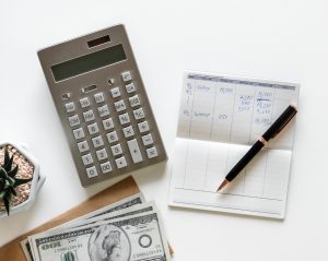 Calculatrice et livre de comptes entreprise sur une table avec des billets